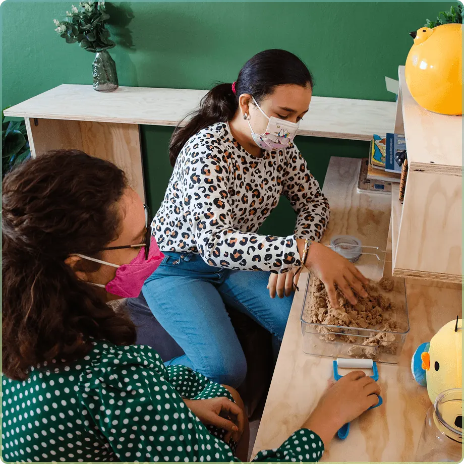 Niña y psicóloga realizando una actividad de juego terapéutico